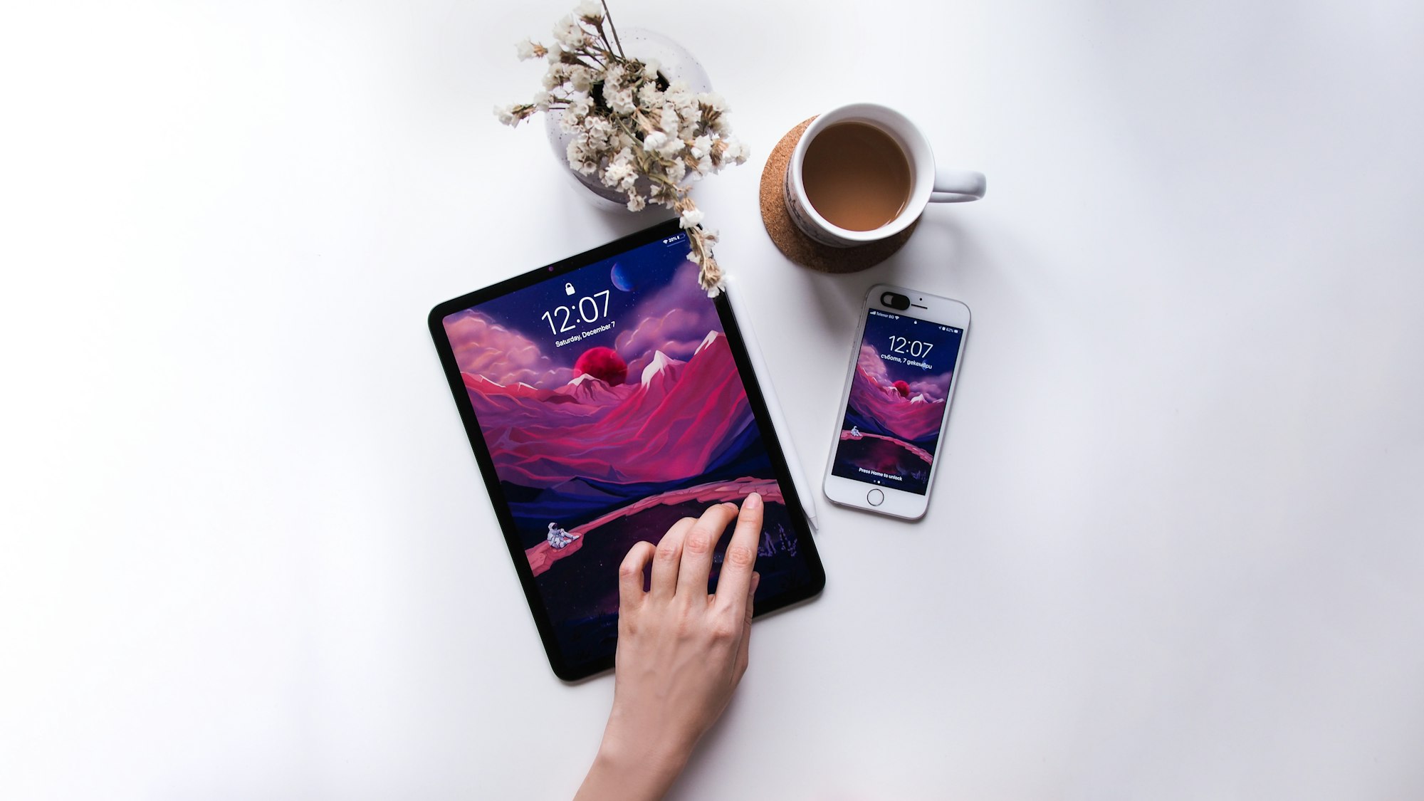 Minimal photo of tablet and phone devices with a purple wallpaper, a cup of coffee and dryed flowers in a white vase on a white clear background.