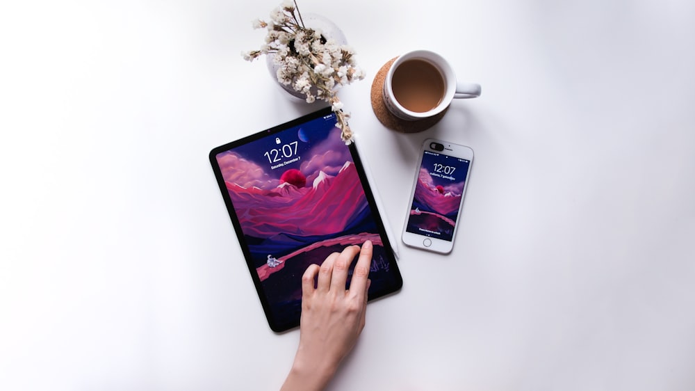 person holding black android smartphone beside white ceramic mug