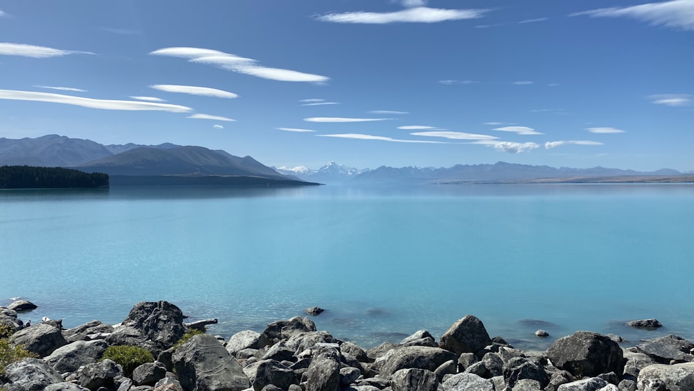 rochas cinzentas perto do corpo de água sob o céu azul durante o dia