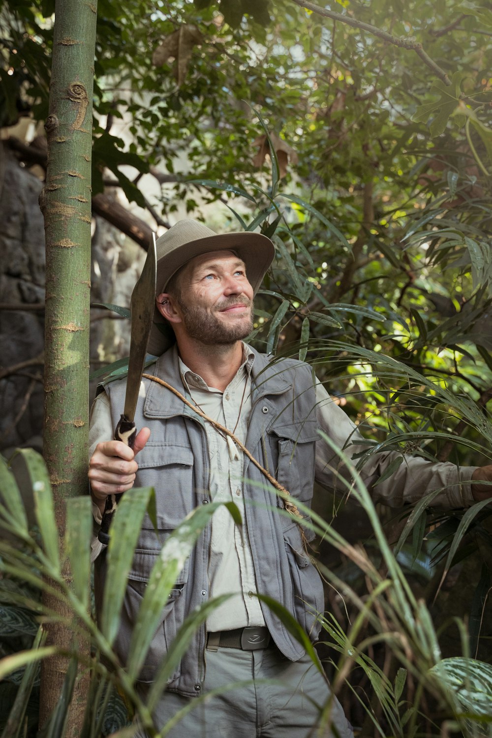 hombre con camisa gris abotonada sosteniendo palo de bambú verde