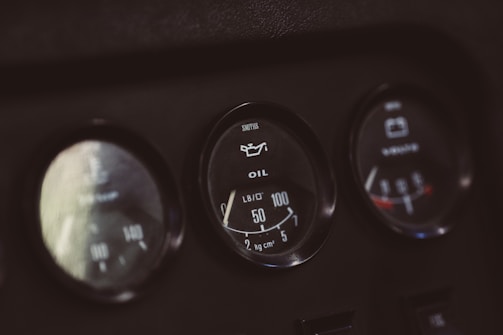 A close-up view of three circular gauges on a dashboard. The center gauge displays an oil pressure indicator with a needle pointing at 40 PSI, accompanied by text labels for oil and pressure units. The other gauges are slightly blurred, with the presence of numerical scales and indicators.