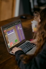 person using macbook air on brown wooden table