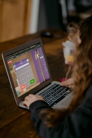 person using macbook air on brown wooden table