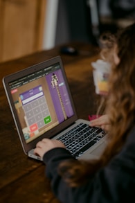 person using macbook air on brown wooden table