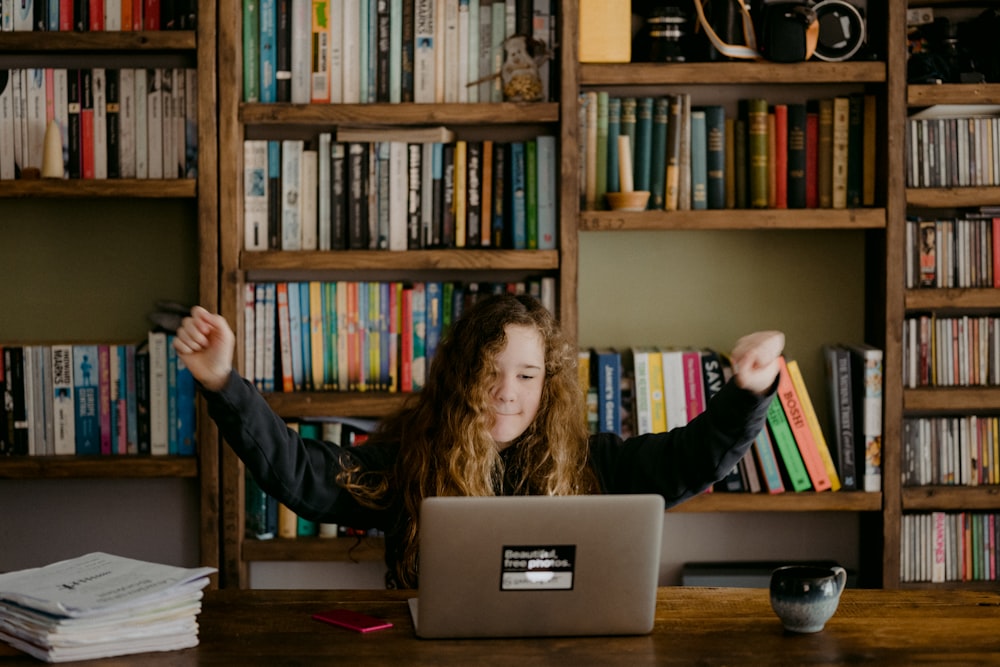 woman in black long sleeve shirt sitting in front of silver macbook