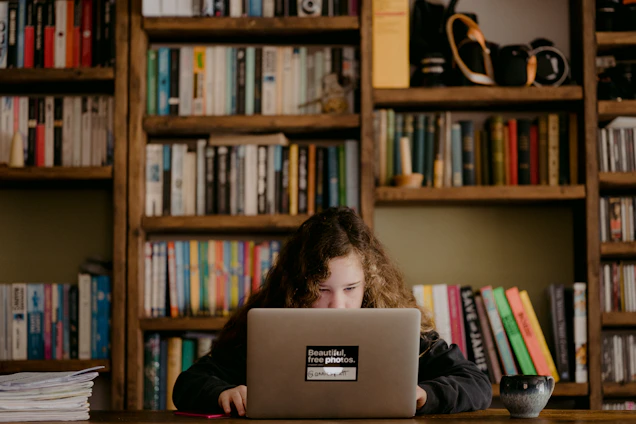 A young student smiling while browsing a modern educational website on a laptop in a cozy study room.
