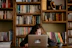 Smiling teenage girl studying maths with a notebook and pen in a bright, cozy room.