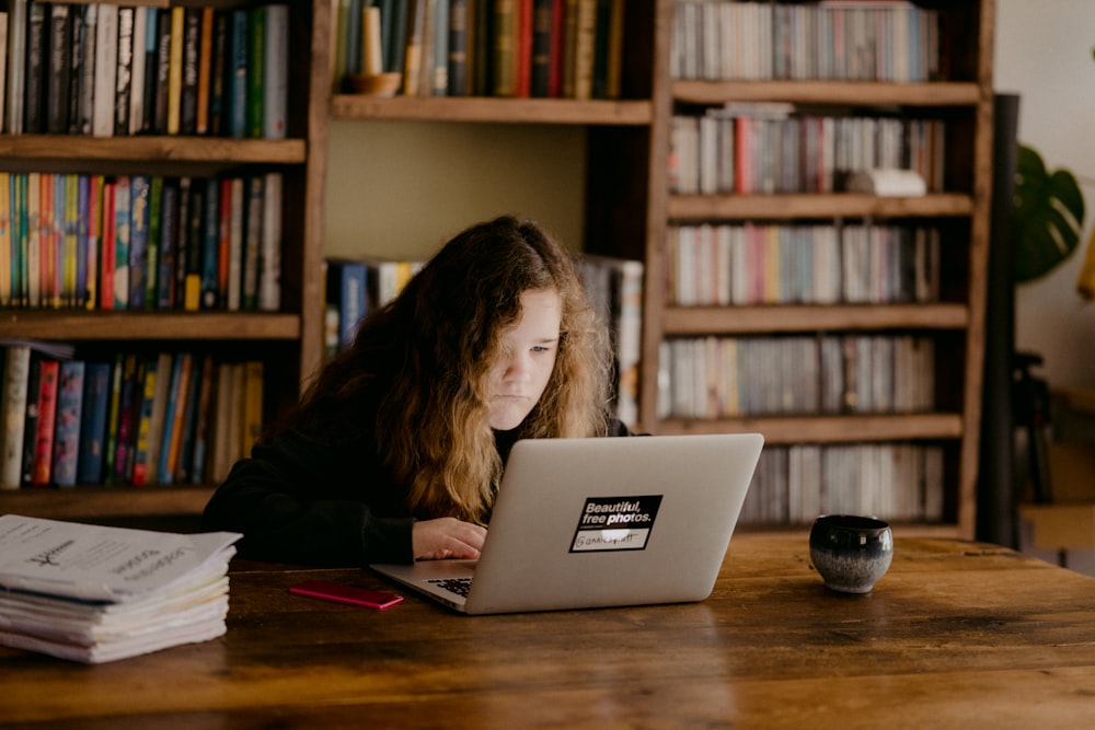 woman in black long sleeve shirt using macbook air on brown wooden table