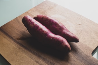 two sweet potato on brown wooden chopping board