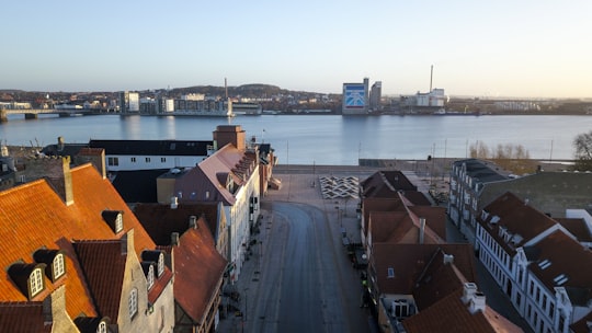 brown and white concrete building near body of water during daytime in Aalborg Denmark