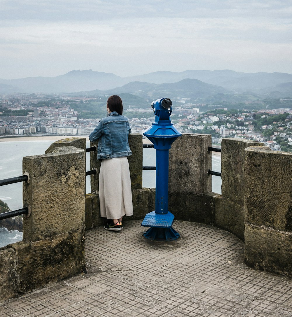 man in grey shirt and blue pants sitting on concrete wall looking at the sea during