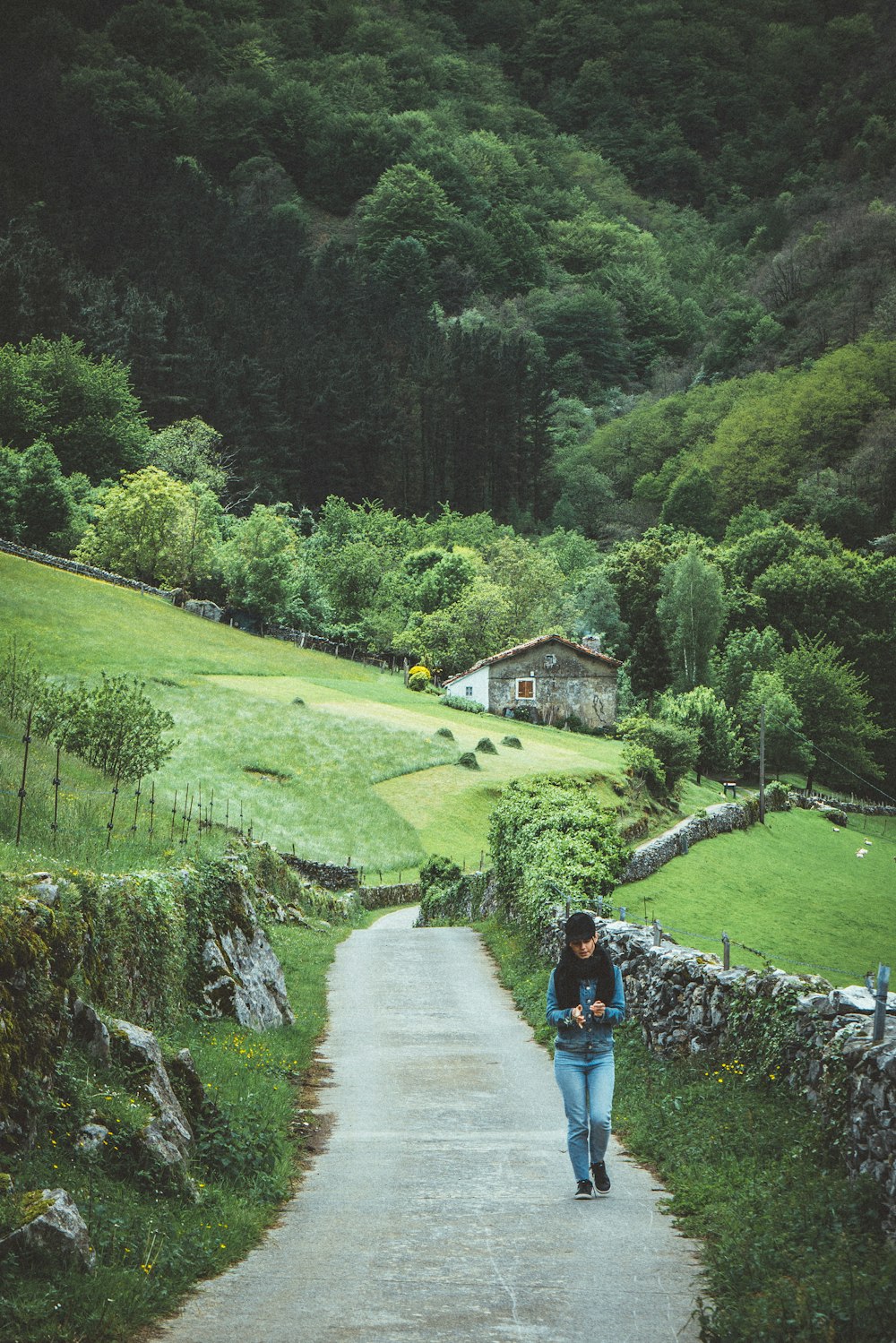 person in blue jacket walking on pathway near green grass field during daytime