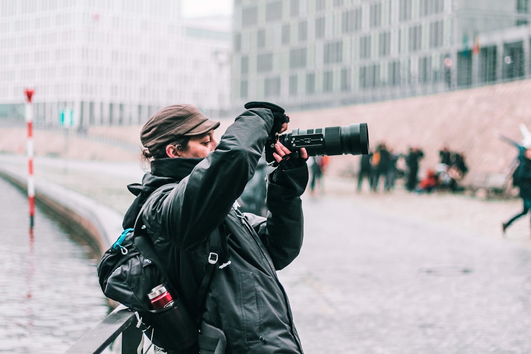 woman in black coat holding black dslr camera