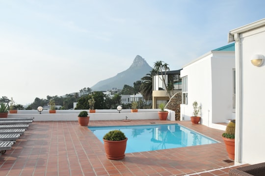 swimming pool near green trees and white house during daytime in Camps Bay South Africa