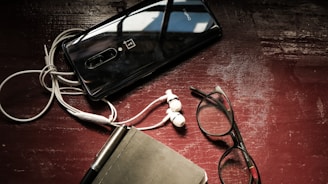 Stylish flat lay of a notebook, headphones, and a microphone on a dark surface.