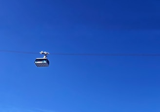 Close-up of a cable car pulley system in motion against a clear blue sky.