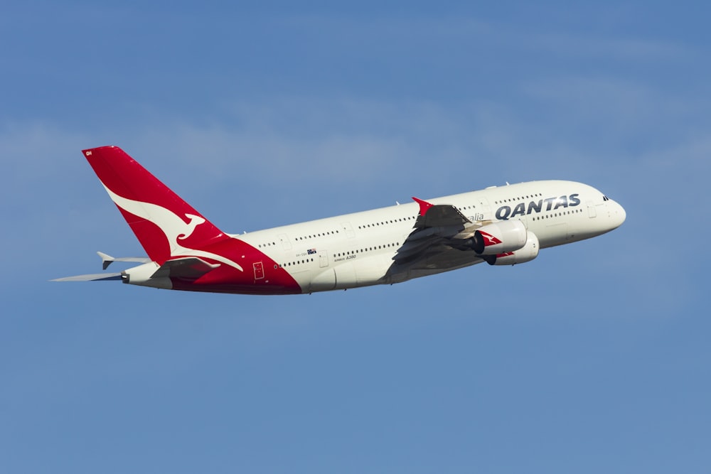 white and red air plane in mid air during daytime