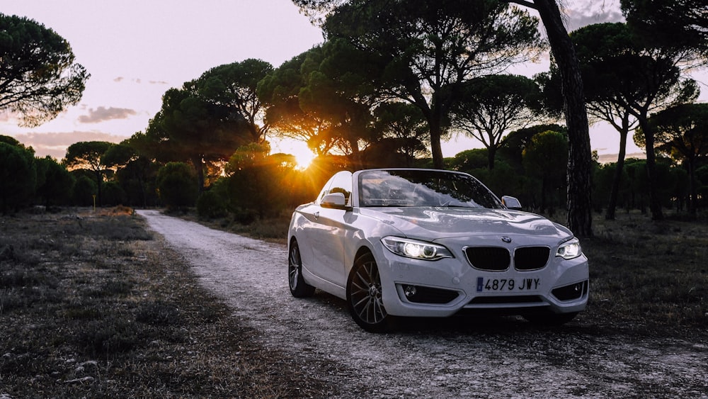 white bmw coupe parked on gray asphalt road during sunset