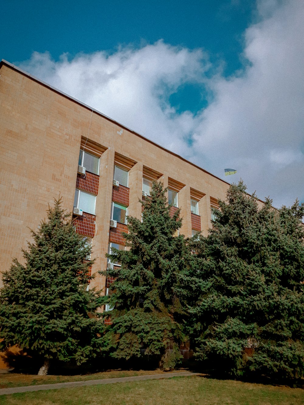 brown concrete building near green trees under blue sky during daytime