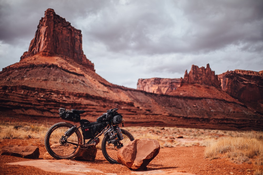 man in black jacket riding black mountain bike on brown rock mountain during daytime