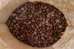 Close-up of perfectly roasted G-1 graded coffee beans in a rustic burlap sack.