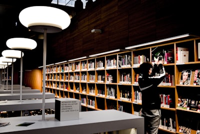 man in black jacket standing near brown wooden book shelves luxembourg google meet background