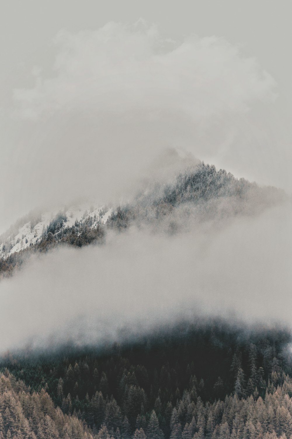 Weiße Wolken über schneebedecktem Berg