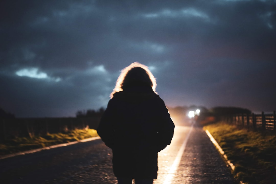 person in black jacket standing on road during daytime