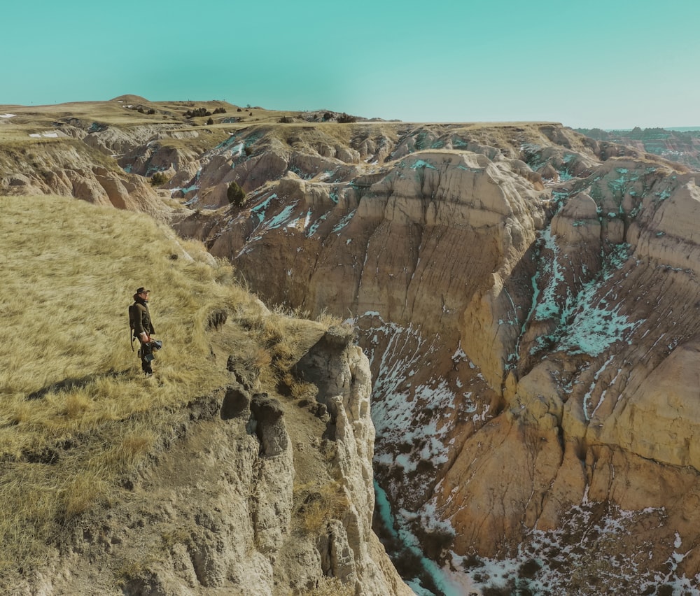 person in black jacket and black pants walking on rocky mountain during daytime