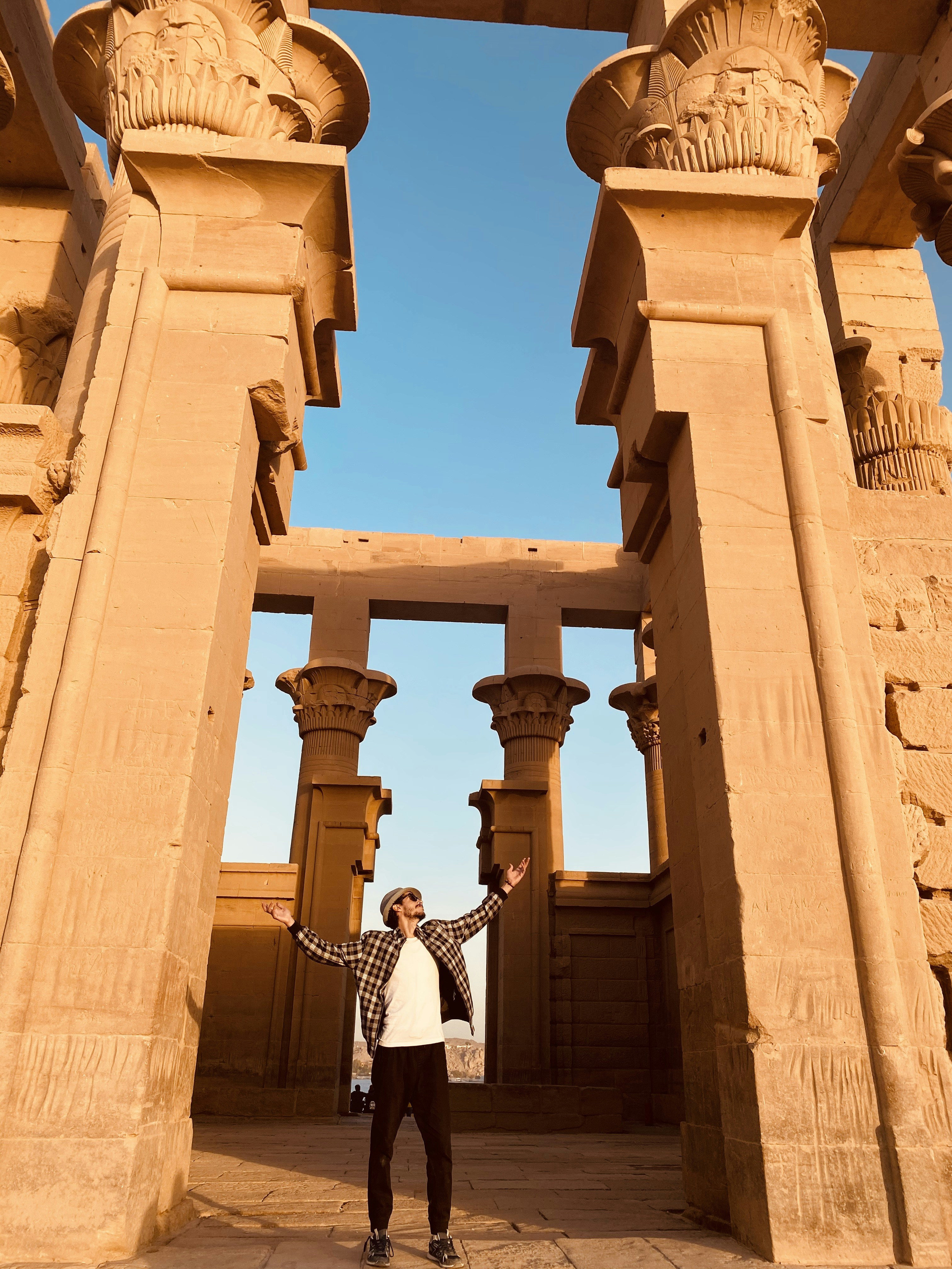 Femme en robe rayée blanche et noire debout sur un bâtiment en béton brun pendant la journée