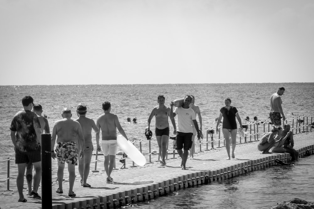 a group of men standing on top of a beach next to the ocean