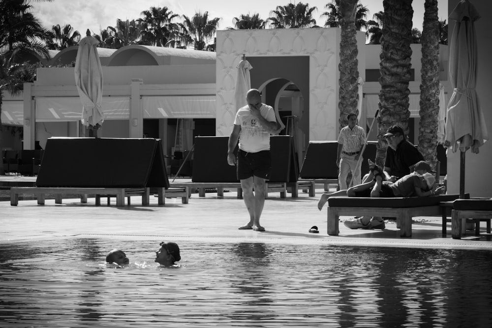 a man standing next to a swimming pool