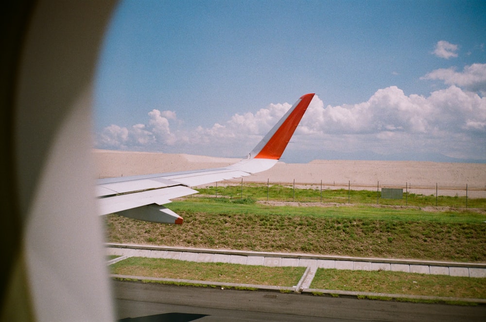 white and orange plane wing under blue sky during daytime