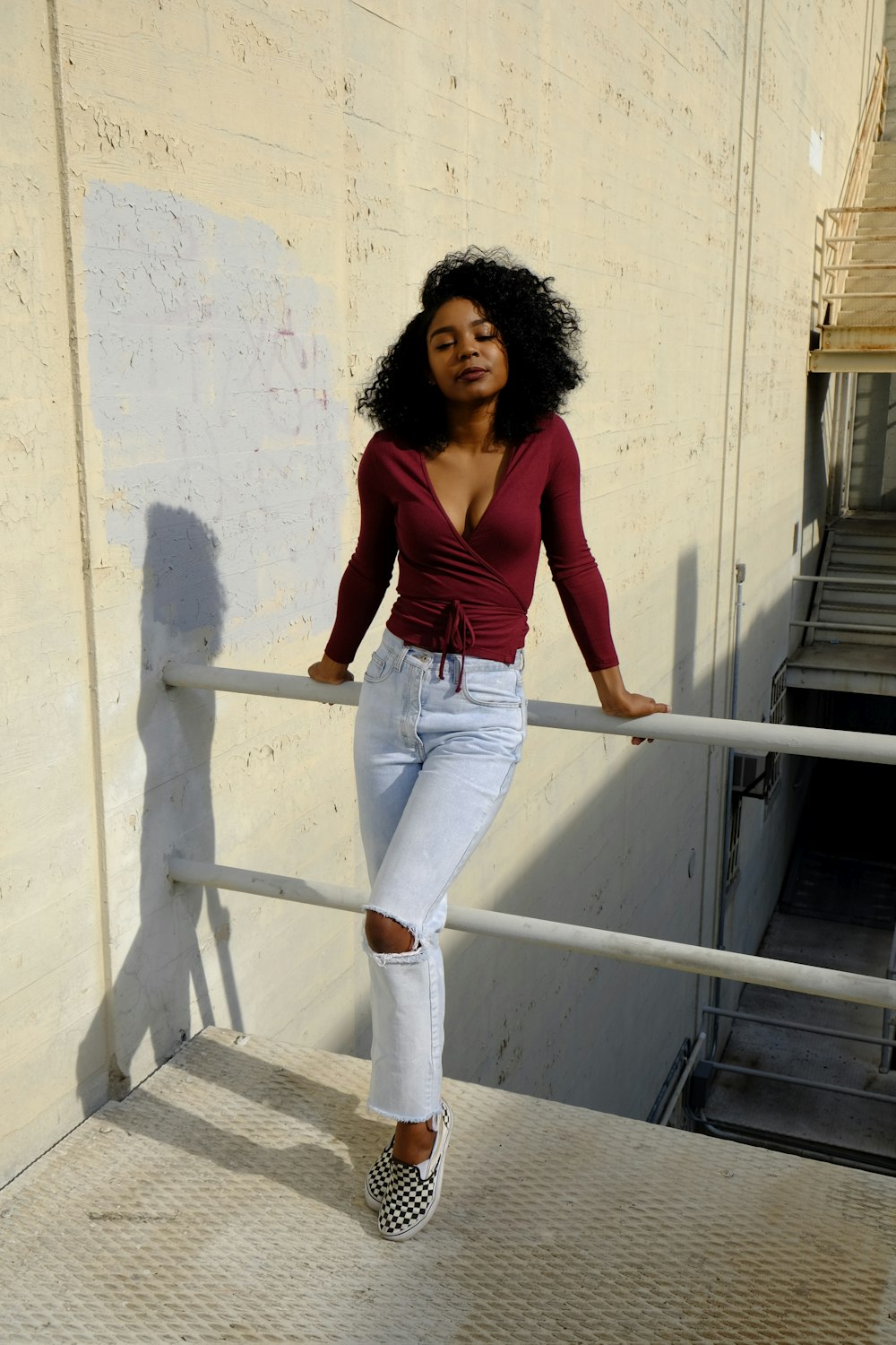 woman in red tank top and blue denim jeans standing on white concrete stairs