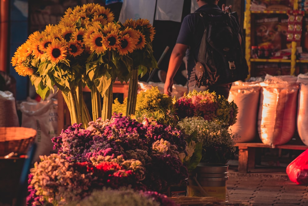 woman in black dress standing beside red and yellow flowers