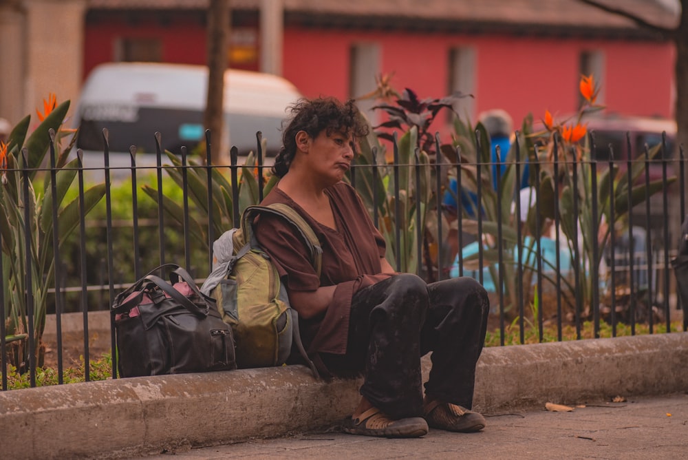 man in brown jacket and black pants sitting on concrete bench