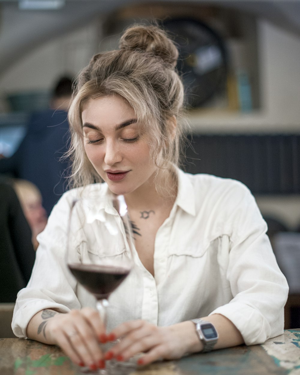 Mujer con camisa de vestir blanca sosteniendo una copa de vino transparente