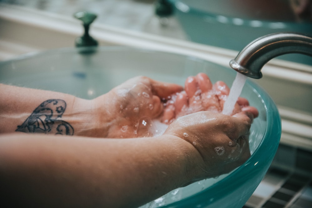 person washing hand on sink