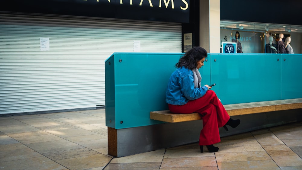 woman in blue jacket sitting on brown wooden bench