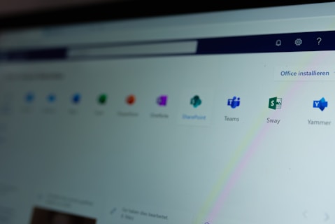 A computer screen displays a webpage featuring a row of icons for various applications such as OneNote, SharePoint, Teams, Sway, and Yammer. The phrase 'Office installieren' is visible on the right side of the screen.