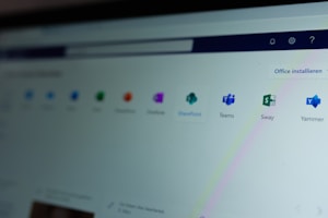 A computer screen displays a webpage featuring a row of icons for various applications such as OneNote, SharePoint, Teams, Sway, and Yammer. The phrase 'Office installieren' is visible on the right side of the screen.