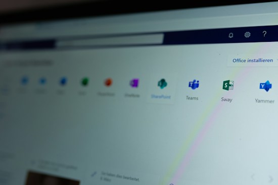 A computer screen displays a webpage featuring a row of icons for various applications such as OneNote, SharePoint, Teams, Sway, and Yammer. The phrase 'Office installieren' is visible on the right side of the screen.