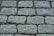 A close-up view of a cobblestone pavement with rectangular stones arranged in a neat, repeating pattern. The surface is slightly rough with visible granules and crevices between the stones.
