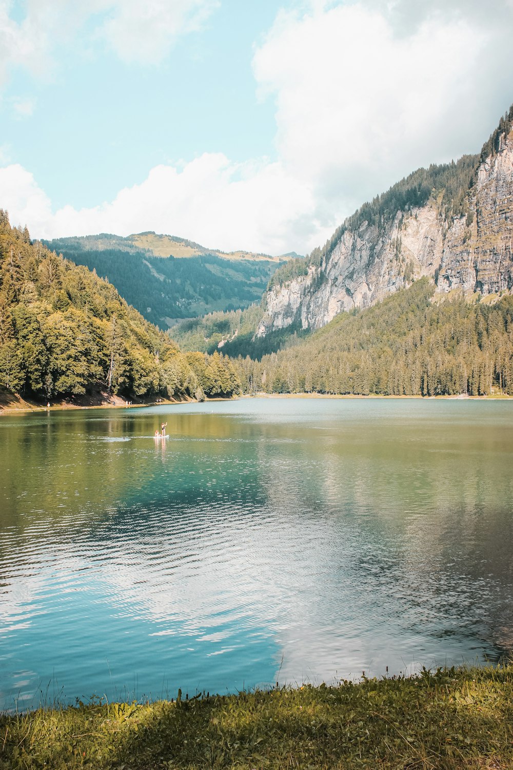 green lake surrounded by green trees and mountains during daytime