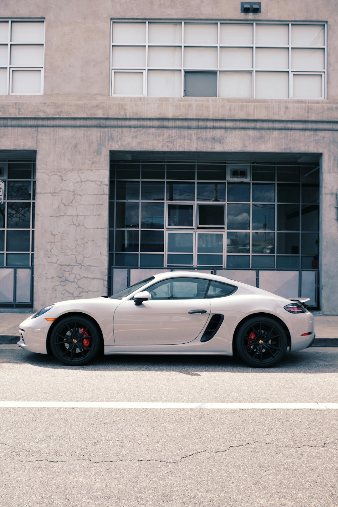 white porsche 911 parked near brown concrete building during daytime