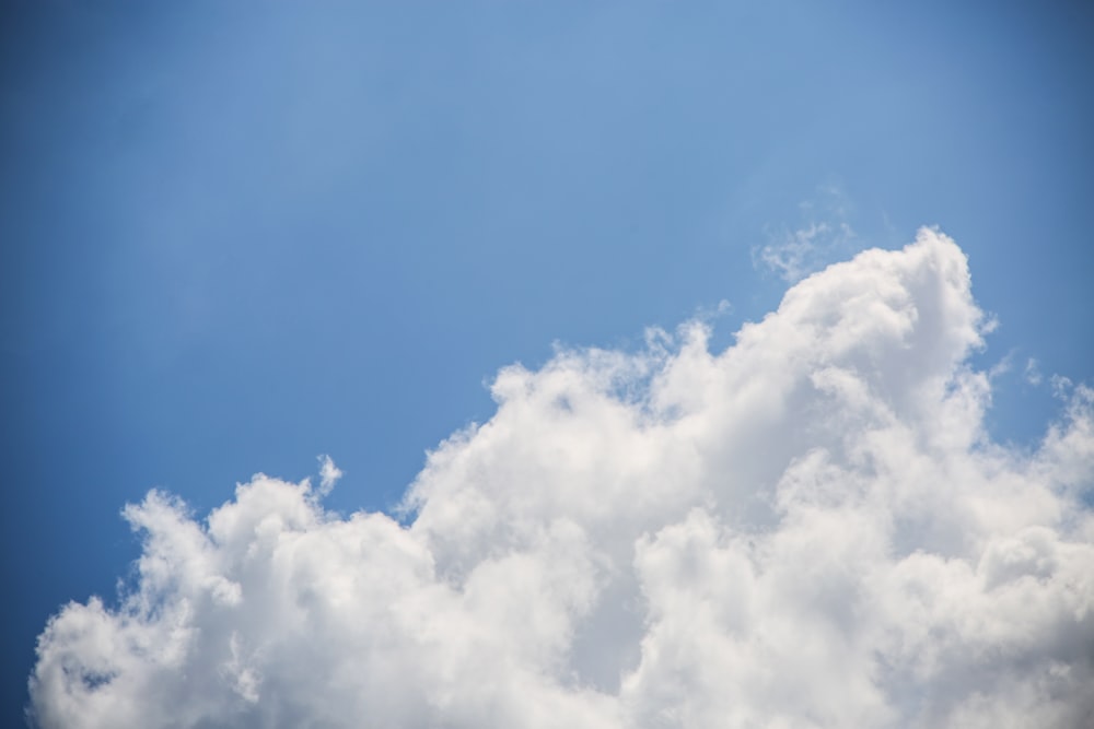 a plane flying through a blue sky with white clouds