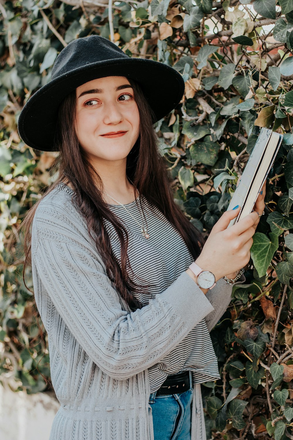 woman in black hat holding book