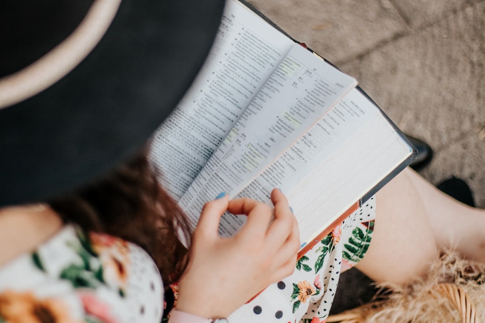 woman in white and red floral shirt reading book