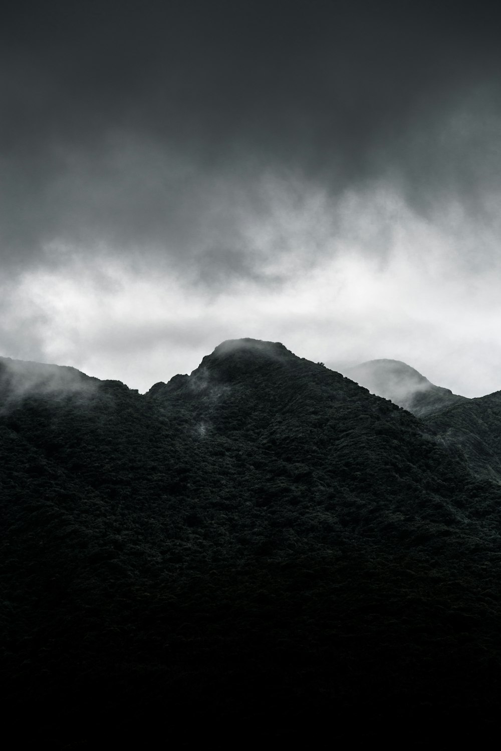 foto em tons de cinza da montanha sob o céu nublado