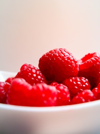 red raspberries on white ceramic bowl